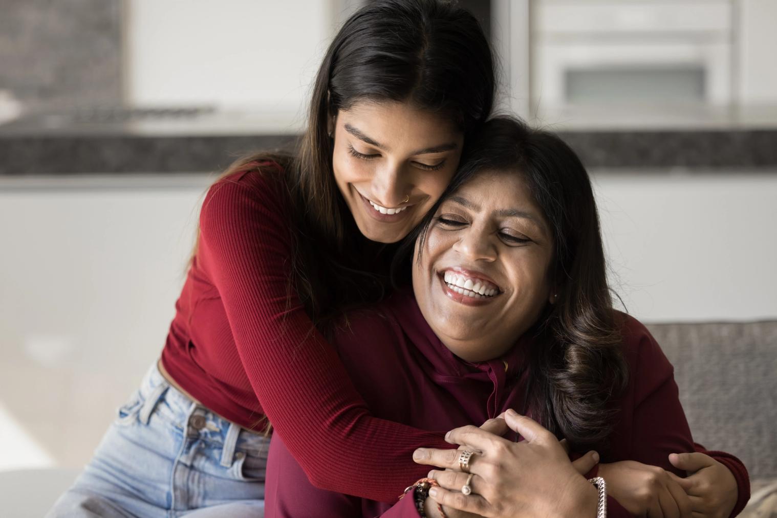 A mother and daughter embracing and laughing happily.