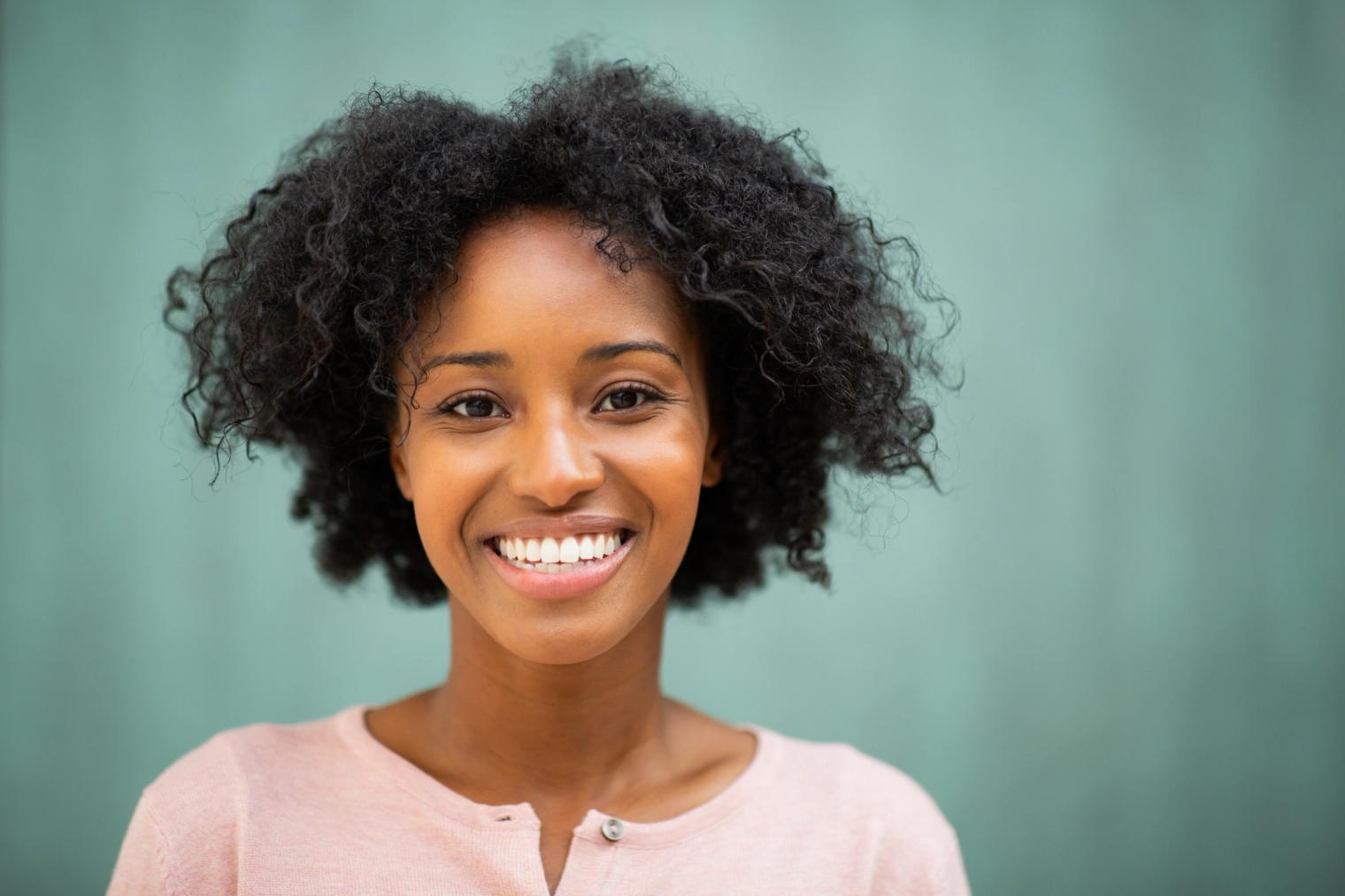 A smiling Black woman with curly hair.