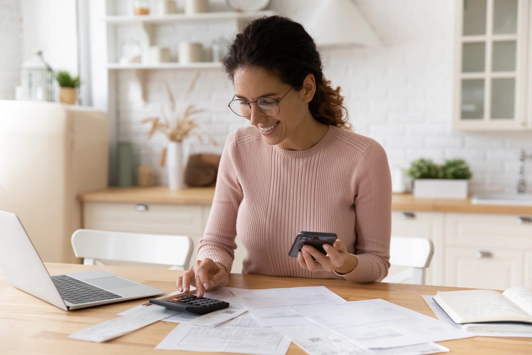 A woman reviewing a budget with a calculator and payment card